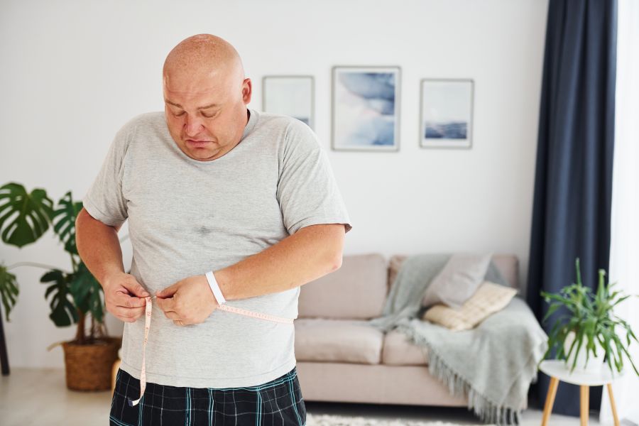 mężczyzna w średnim wieku mierzy obwód brzucha w domu